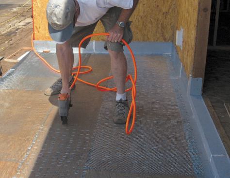 The author installs galvanized expanded lath on the deck, lapping it onto the flashings and fastening it down with closely spaced staples.