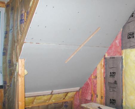 With tall sloped ceilings that require two full courses of drywall, the author fastens a 1-by cleat to the bottom edge of the upper sheet with a single screw, then rotates the cleat to lock the lower sheet in place.