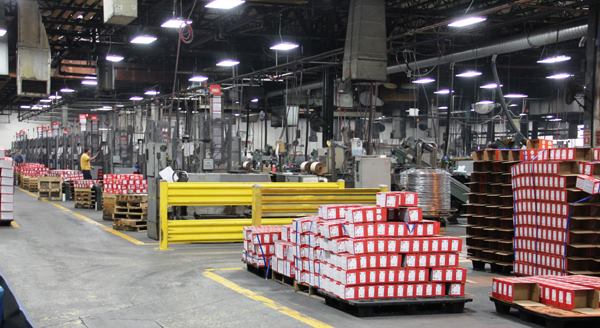 A variety of paper-collated stick nails are being made in this part of the plant. The boxes you see are empty and waiting to be filled. Unlike coil nails, which are delicate and need to be boxed by hand, stick nails can be boxed by machine—but the box is closed by hand so a person can inspect the fasteners before they go out.