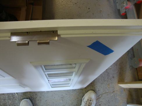On a glazed door slab, the retainer molding has an interior side. To maintain the proper orientation while working on the door, Greg puts a piece of painter’s tape on the upper inside corner of the slab.