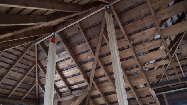 In the upper story, long temporary strongback posts topped with bottle jacks were used to lift the ridge of the complex hip roof, while comealongs were used to draw in the kneewalls of the house, which had splayed outward over the years.