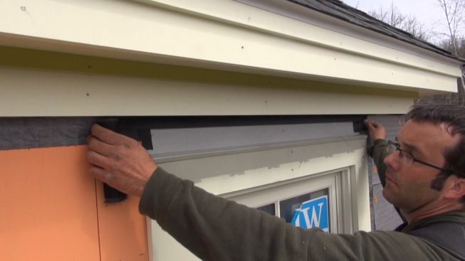 Insect screen is installed over the window cap flashing to allow for a gap between the flashing and siding for airflow and drainage.