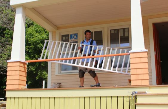 Pollard carries the rail assembly into position between the porch columns.