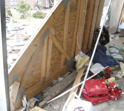 Gable-end truss seen from behind. The gable triangle was intact, with the OSB sheathing still in place — it's the connections that failed.