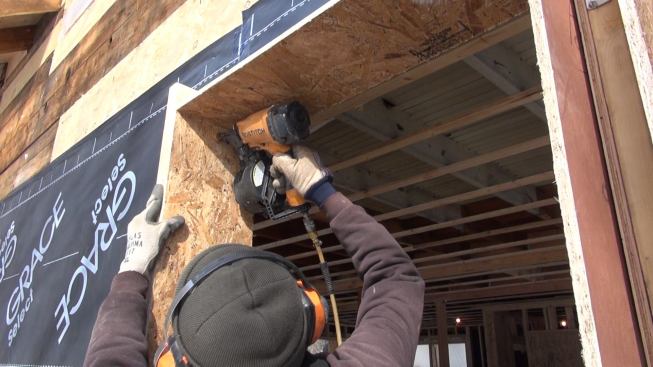 Using a 3-inch rip of 2x4 as a depth gauge, carpenter Ed Muennich nails an OSB extension window buck into the existing wall framing.