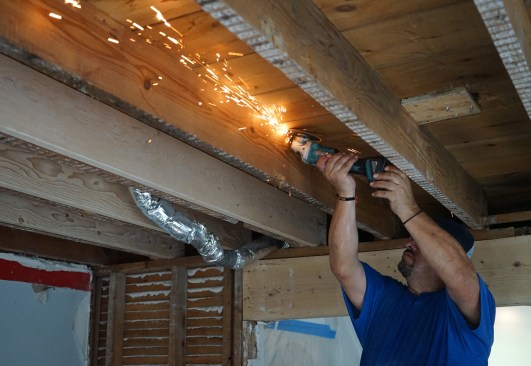 Ernesto Bonilla of Great Lake Builders cuts flooring nails so sister joists will fit tight to the existing ones.