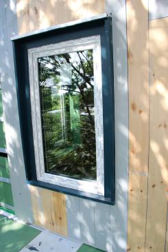 Where the vertical ship-lap board siding butts against the trim, the joints are left uncaulked to promote drying.