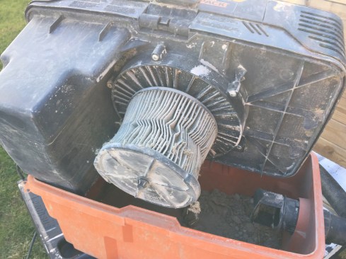 The pleated paper filter is typical. It’s held on by its rubber body though, not a wing nut, so there’s nothing to drop in the dust and customer’s cat hair when removing it for cleaning.