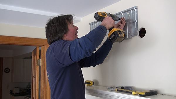 While Dave Ragsdale works on the outdoor unit of the system, Chris Blaisdell attaches a mounting bracket for the indoor side of the system to an interior wall.