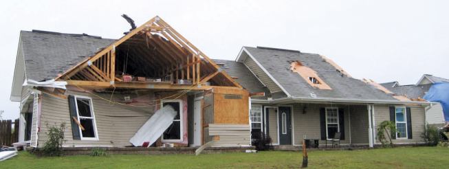 Another home in the same neighborhood lost its garage door and had its front garage wall pushed in — apparently by wind pressure, as there was no sign of impact. Gable-end failures occurred on the front and right side of the house.