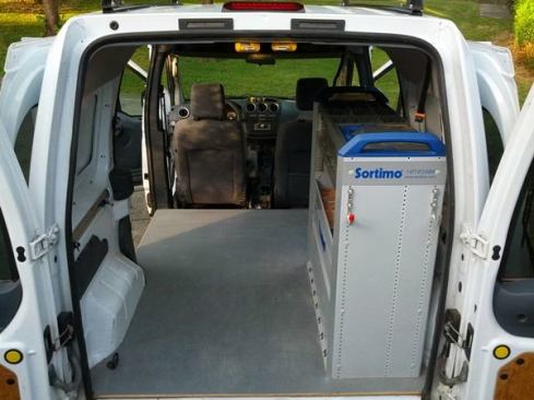 The cargo space measures 59"x75" (minus the wheel wells), and is 51" high. The shelving unit takes up some of this space, but provides a ton of organization. A hose hanger cable-tied to the shelf carries air hoses, and an inverter clamped in place allows me to charge batteries on the road (there is a factory-installed 12-volt socket on the center console that is always live). I can fit an entire finish toolkit inside the van by employing the strategies described in the following photos.