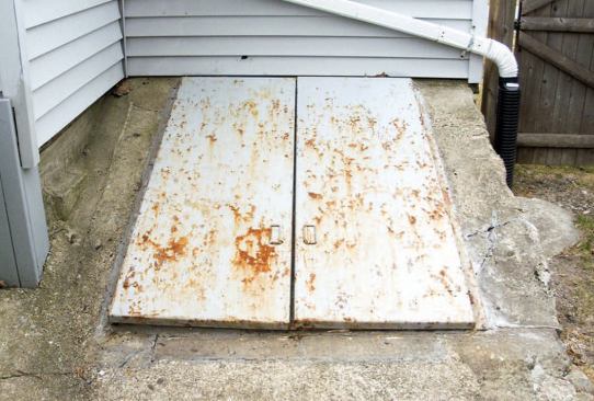 Existing Conditions:  I occasionally get asked to replace basement access doors. Usually the doors are in pretty bad shape, and more often than not, the bulkhead itself is in need of repair. On the job shown here, for example, the concrete and stone base was beginning to crumble, and the top surface was cracked and uneven (B). When I first looked at the job, the gutter downspout terminated between the house and the bulkhead, to the left of the doors; it had been dumping water in the corner for years, saturating the masonry. By the time I returned to start work, the homeowner had taken care of this, directing the downspout to the right of the bulkhead and away from the house.