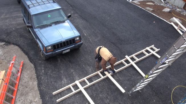 While Todd and Caleb install the fabric, Steve assembles an outrigger on the ground.