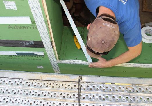 Designer and project manager Steve Daly applies Siga Wigluv tape to the edges of the window opening for waterproofing.