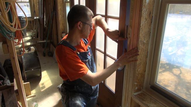 A Thompson and Johnson crew member seals French doors with masking tape as the crew prepares for the blower door test.