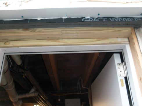Attaching the Cap: I frequently see rot around the sill on unflashed bulkhead doors; applying a rubber flashing under the existing housewrap before installing the unit is critical. Before sliding the cap into place, I always apply a thick bead of Phenoseal to the top edge of the cap where it meets the house, then secure it with pocket screws against the membrane, leaving a watertight joint.