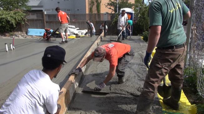 Towards the end of the pour, too much concrete piled up in front of the screed, and the screeding was tough going for the men on either end of the tool. Here, Steve Daly removes excess concrete from in front of the screed.
