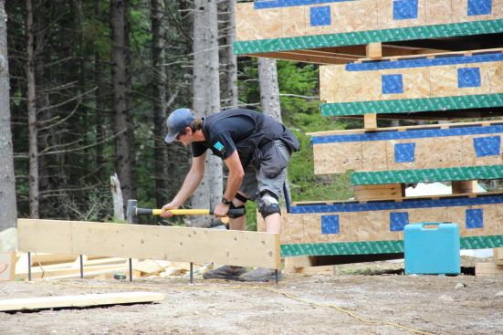 Walls have to be precisely plumbed in order for the factory-built floor sections to mate up properly with the walls. Here, crew member George Reefer sets a bracing board near the slab, driving the rebar spikes attached to the board into the compacted fill.