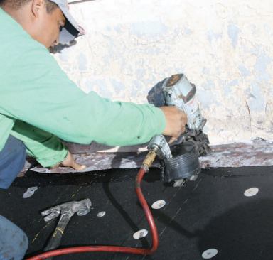 He nails the flashing down to the tar with ringshank nails.