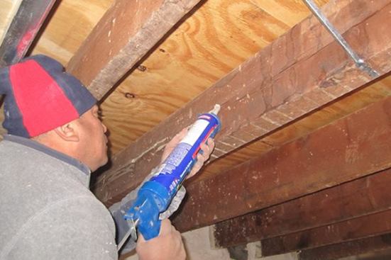 Structural issues aren’t the only issue to address with the existing wood framing, says contractor Jose Maldonado. Here, a worker caulks a long crack in a wood joist. This is an air-tightening measure, explains Maldonado: The crack runs all the way to the end of the joist where the wood is buried in the brick party wall. During air-sealing, the brick and the joist ends are sealed with Sto Diamond Cote elastomeric coating; but the crack in the joist can bypass that seal and create a leak that will show up during blower door testing, if not attended to during the framing stage. “I have had that happen before,” says Maldonado.