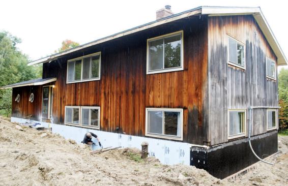 After cleaning off the stem walls and reapplying asphalt dampproofing, workers installed a double layer of 1 1/2-inch-thick XPS foam, staggering and foaming the joints to minimize air intrusion.