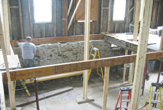 Instead of trying to fasten new floor joists to the rotten sills, the crew placed new 2x4 pressure-treated sills on the inner portion of the wide foundation, then set a double-LVL rim joist on top to catch the ends of the new I-joists.