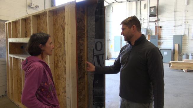 Using a prototype, Chris Corson discusses the construction details and building science characteristics of his panelized wall system with architect Rachel Conly, visiting from Portland, Maine. Consisting of an OSB-sheathed 2x4 interior frame, then an insulation cavity formed by exterior-applied wood I-joists, the assembly is designed to be air-tight at the level of the OSB, but vapor-open to both the interior and exterior
