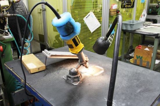 A DeWalt die-grinder has been adapted for use in the factory. It contains a sort of chamfering bit the operator uses to smooth the edges of the thumb notch used to flip a blade out one-handed. There is a screen built into the bench; it probably covers a vacuum intake intended to collect metal filings. As you can see, it doesn’t get them all. That blue filter-like material on the end of the tool was probably put there to keep metal filings from getting into the motor. This is one of the few non-automated machining operations I saw in the plant.