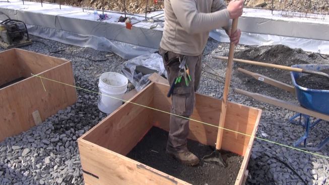 Tim compacts the crusher run layer before adding an additional protective layer of sand.