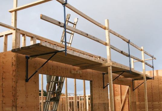 Previously, the author paid thousands of dollars in OSHA fines for fall-protection violations on this job site, because his crew was walking the top plates to set trusses and accessing the plate usingstepladders. Now the crew sets up OSHA-compliant scaffolding with railings and toeboards at the building eaves.