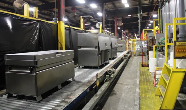 When the welding is complete boxes are placed on an automated conveyor that advances them towards equipment that will clean them prior to powder coating. The boxes shown here were assembled in the flow line, just beyond the divider behind them. Click here for video.