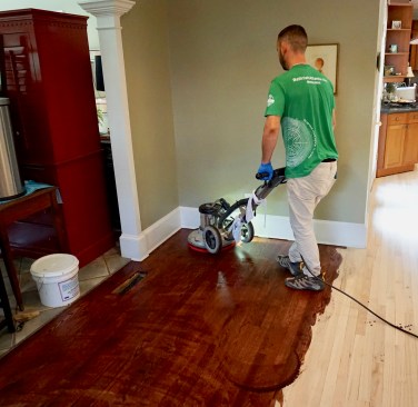 After 10 to 15 minutes of “dwell” time, a crew member comes in behind Mike to further work the oil into the wood with a buffer fitted with a red buffing pad.