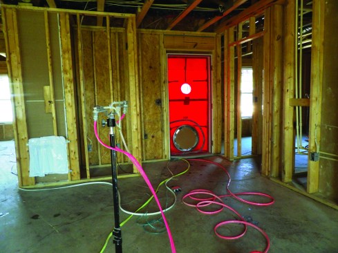 While a blower door pressurizes the house, emitter nozzles pump a fog of acrylic sealant into the building air. Walls can be exposed sheathing or finished with drywall.