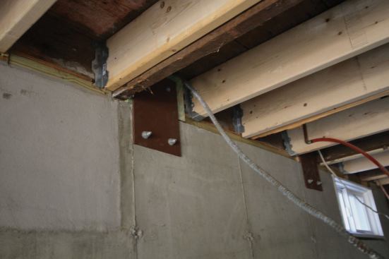 To tie the building to the foundation, we had a steel supplier cut and punch bolt holes in 1/4-inch steel plates, which we prime-painted and lagged to the foundation using a Simpson SET-XP epoxy anchoring system.