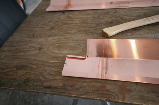 The copper pieces are cut to accommodate two locking seams. Then, the corners of the apron piece are notched 3 1/2 inches in from the ends, the inside corner is cut at a 45-degree angle, and two 1/2-inch seams are folded over.