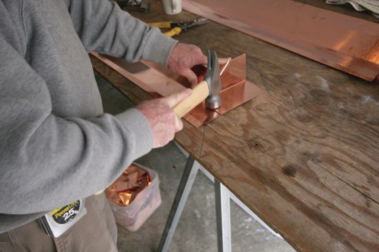 The seams are hammered flat and temporarily locked together with a small dimple created by a light tap on a nail.