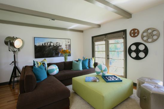 Deviating slightly from the look found in the other rooms in the house, a punch of color, custom pillows, and other interior design elements provide a touch of theme for a fun and refreshing environment. Ceiling beams were painted and installed to give the room more dimension and architectural interest, while two sets of French doors featuring horizontal mullions and set to swing outward allow dual means of egress to the outdoors. 