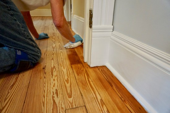 He cuts it in neatly to the baseboard, working a swathe about 6 inches wide around the perimeter of the room.