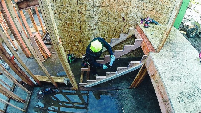 Two-by risers provide nailing for each tread. The author starts by applying adhesive to the stringer edges.