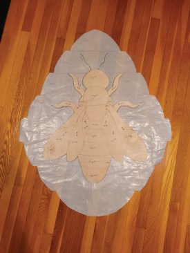 To make the inlay of a bee, the author transferred his design to plywood, cut out the pieces with a scroll saw, then reassembled the pieces on a piece of plastic to show clients the design in full scale. He drew arrows on the patterns to indicate grain direction.