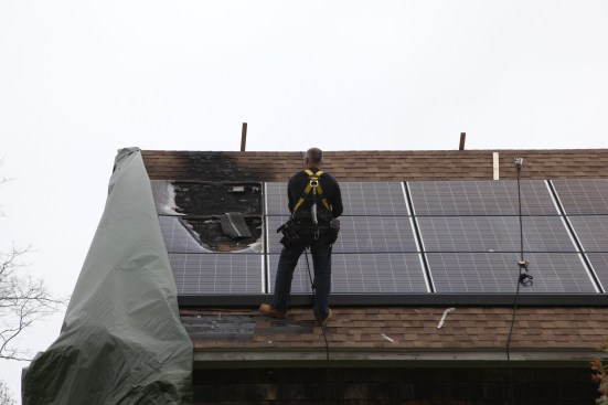 A crew from the solar company peeled back the tarp for investigators to inspect the fire damage and to determine a cause.