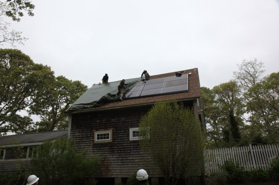 Before the crew  could remove the panels, they needed to peel back the tarp that had been protecting the area of the roof damaged by the solar-panel fire.