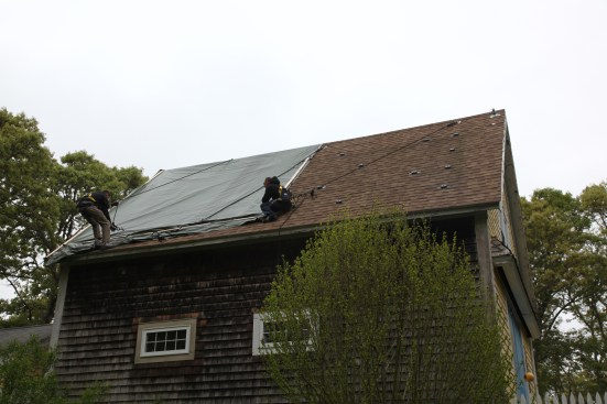 After removing all of the panels, the crew reattaches the green tarp one last time to protect the roof until the roofers could replace the damaged shingles. The mounting pucks for the panels remained in place until the roofers stripped the shingles from the damaged roof.