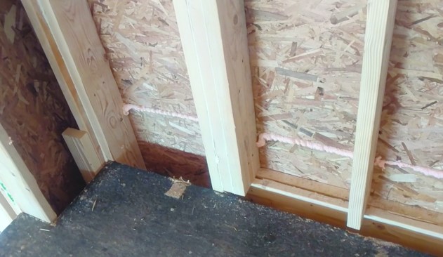 Here, the framing juncture between a stair landing and a balloon-framed wall has no solid blocking where drywall will meet the floor.
