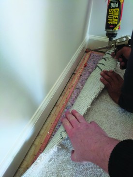Without the blocking, air pours through the gap beneath the baseboard. The author pulls back the carpet at a landing in a finished house and seals the joint with gun foam.