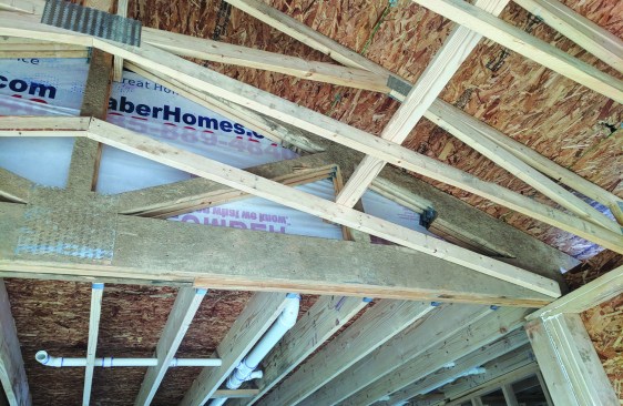 A scissors-truss roof abuts a carrying beam for a floor system ...