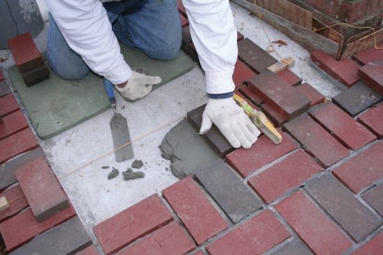 When the author taps or presses the brick into the mortar bed, he avoids using the handle of his trowel so that he doesn't sprinkle the face of the bricks with mortar and stain them. The torpedo level is handy for determining when the brick is even with its neighbor. 