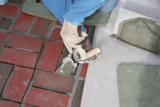 The author cuts a ½-in. wide slice from the flattened mortar on the hawk, positions the slice over the joint, then pushes it into the joint with a small margin trowel. 