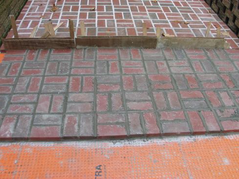 Expansion joints were needed wherever the paving abutted vertical surfaces. To keep mortar from squeezing into the ½-in. wide expansion joints in the field, the author inserted ¼-in. slats of wood wedged in place by shims.