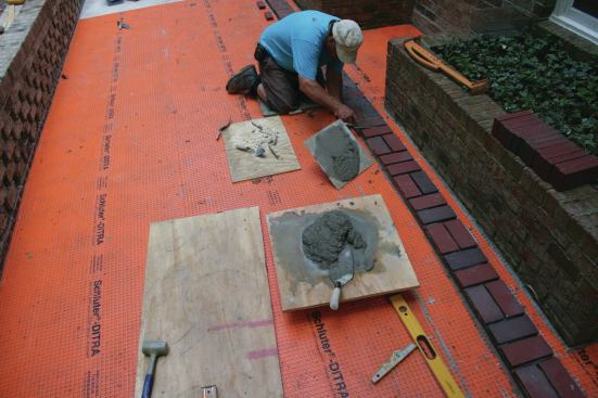 Modular pavers measure 7 5/8 inches by 3 5/8 inches and are designed to be laid out in 8-inch increments (with 3/8-inch mortar joints). Here, the author installs the first of two parallel columns of bricks, which he'll use as story poles as he lays the pavers in between them.  